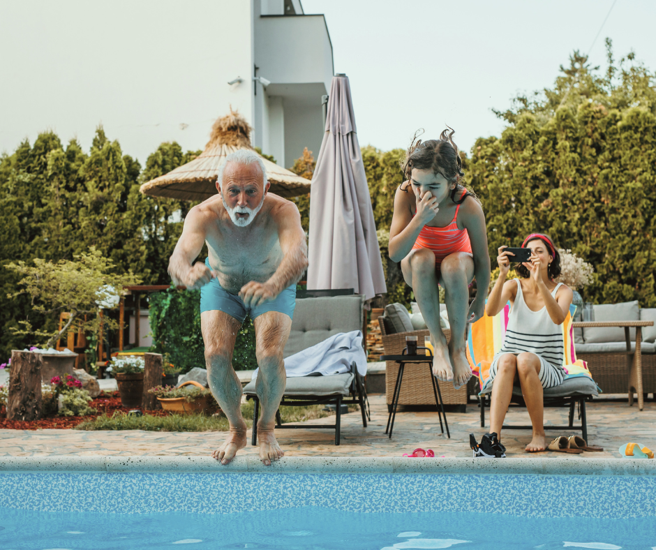 Multi-Generational Vacations: Stress-Free Planning with DVC Advantages - DVC Advantages Grandpa and granddaughter jumping into a pool with a mom in the background capturing the moment with a picture.