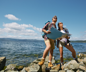 Couple with a map on the rocks near the ocean.