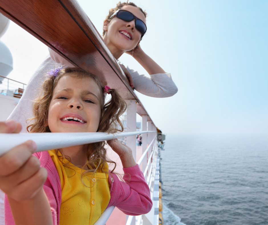 Mom and daughter smiling and looking out over the water from a cruise ship.