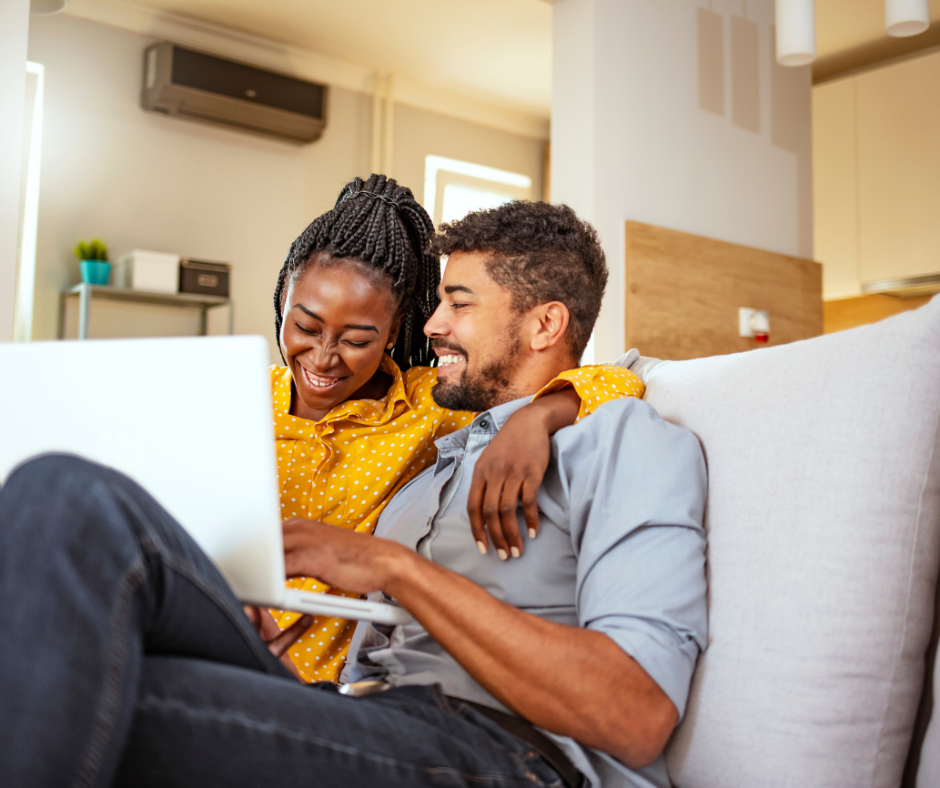 Young couple at home looking at a computer and smiling.