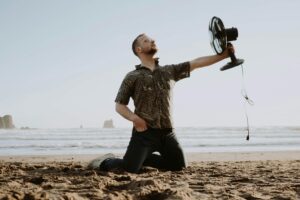 Man on the beach holding his fan, happy that he has it.