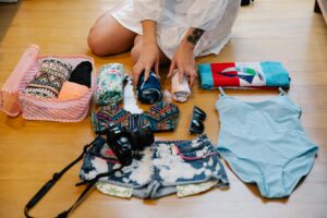 Packing Travel Essentials for Vacation - DVC Advantages Woman packing travel essentials into a suitcase on her bed before a trip